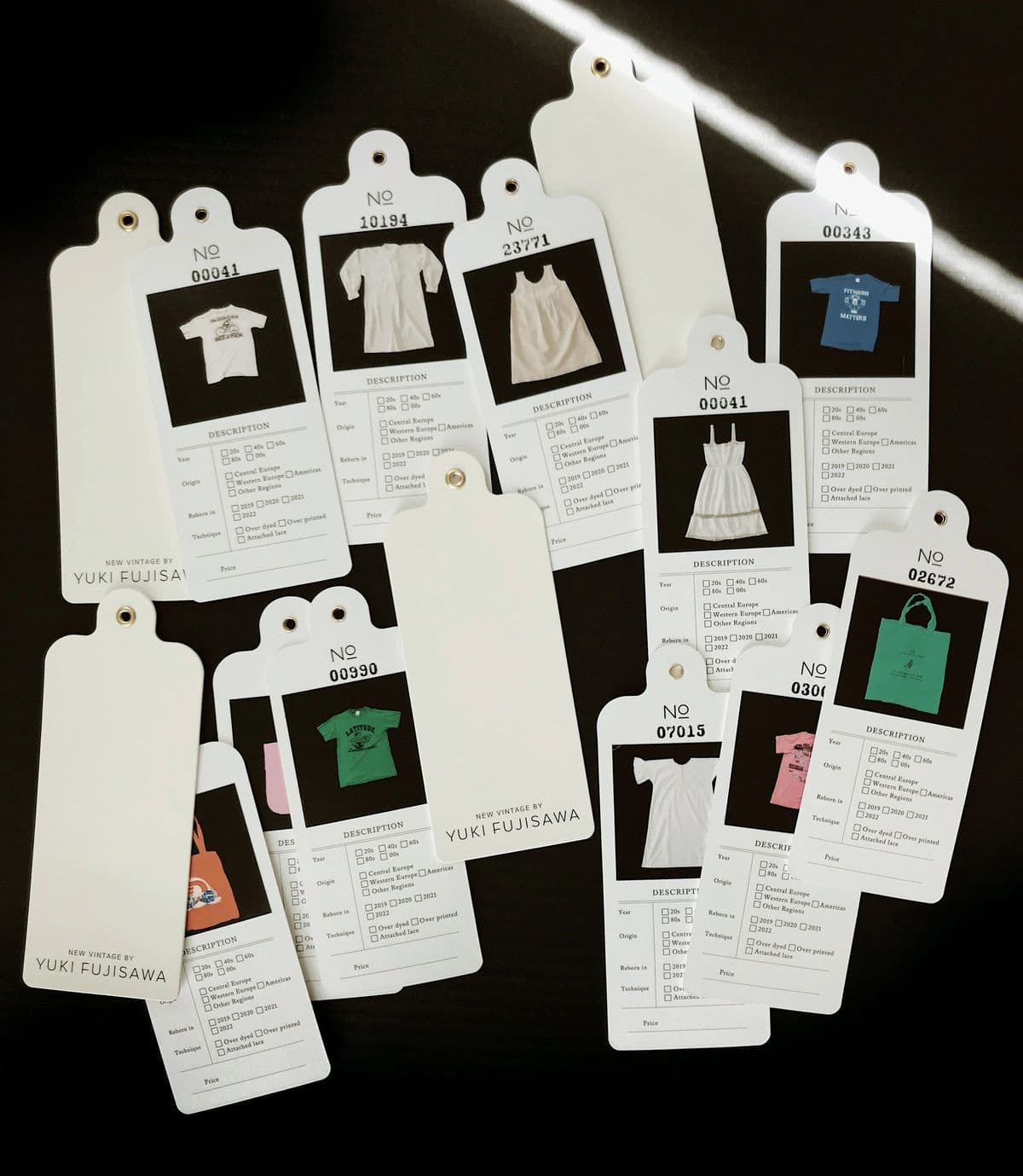 Numbered archive hang tags, each with a small garment photograph and a specification checklist