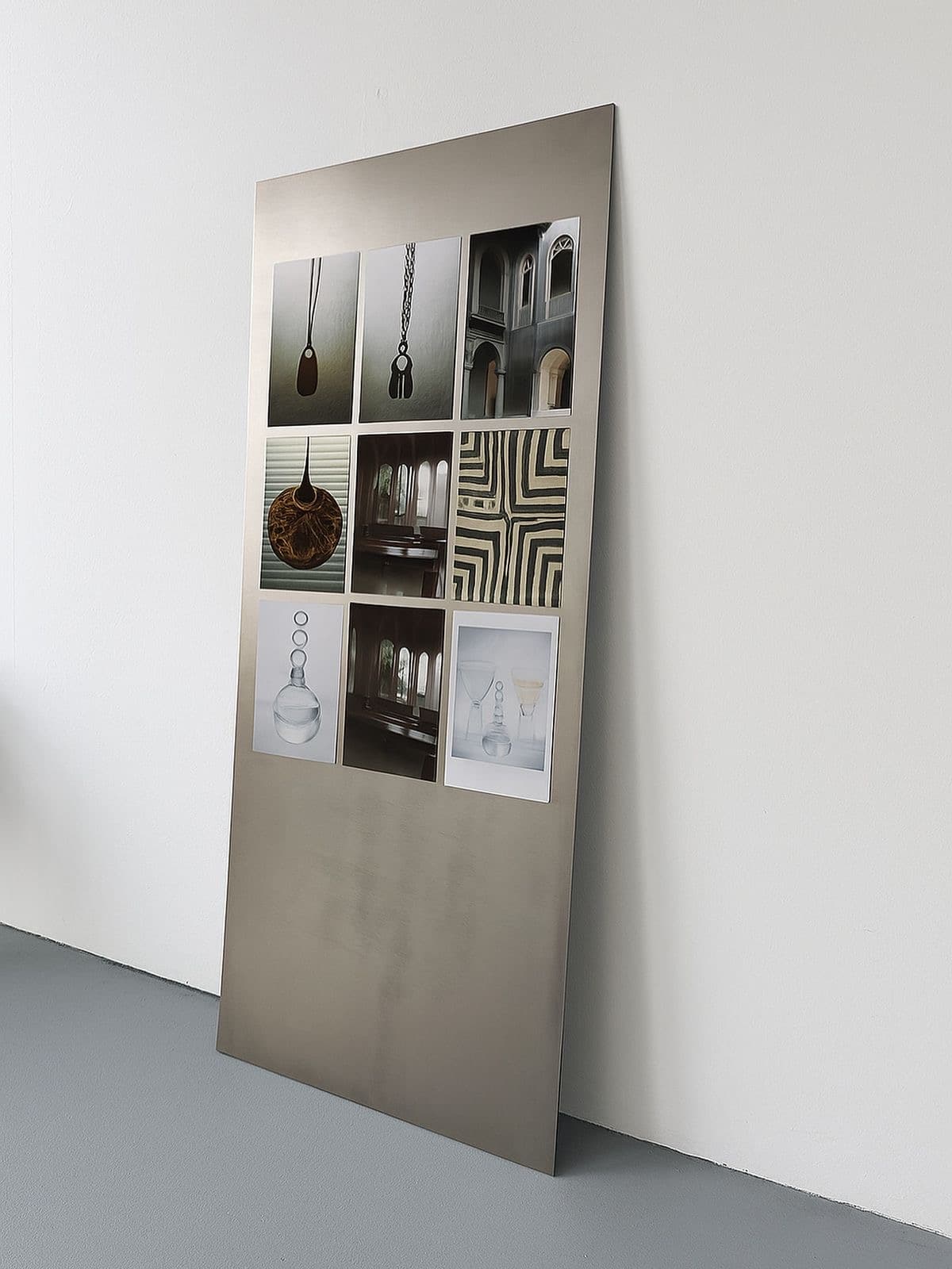 A grid of reference photographs on a brushed-steel sheet leaning against a wall