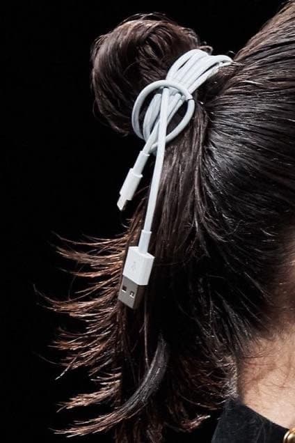 A white USB cable tied into a hair bun