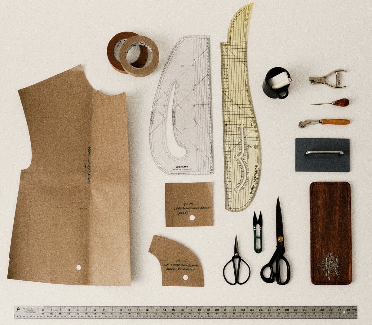 Kraft pattern pieces, french curves, a metre rule and shears laid out on a cutting table